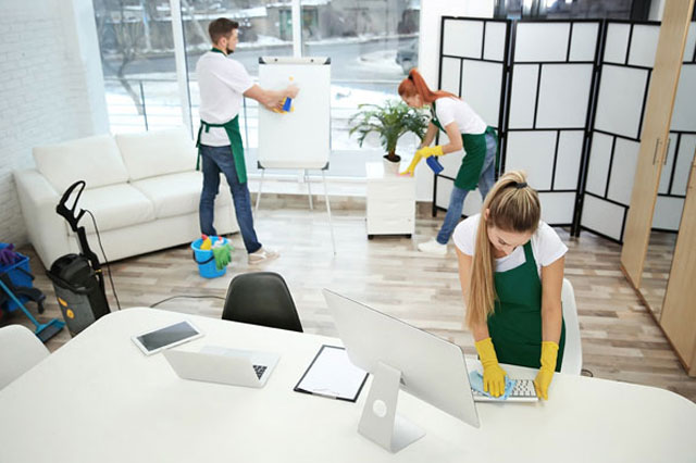 three people in aprons cleaning an office